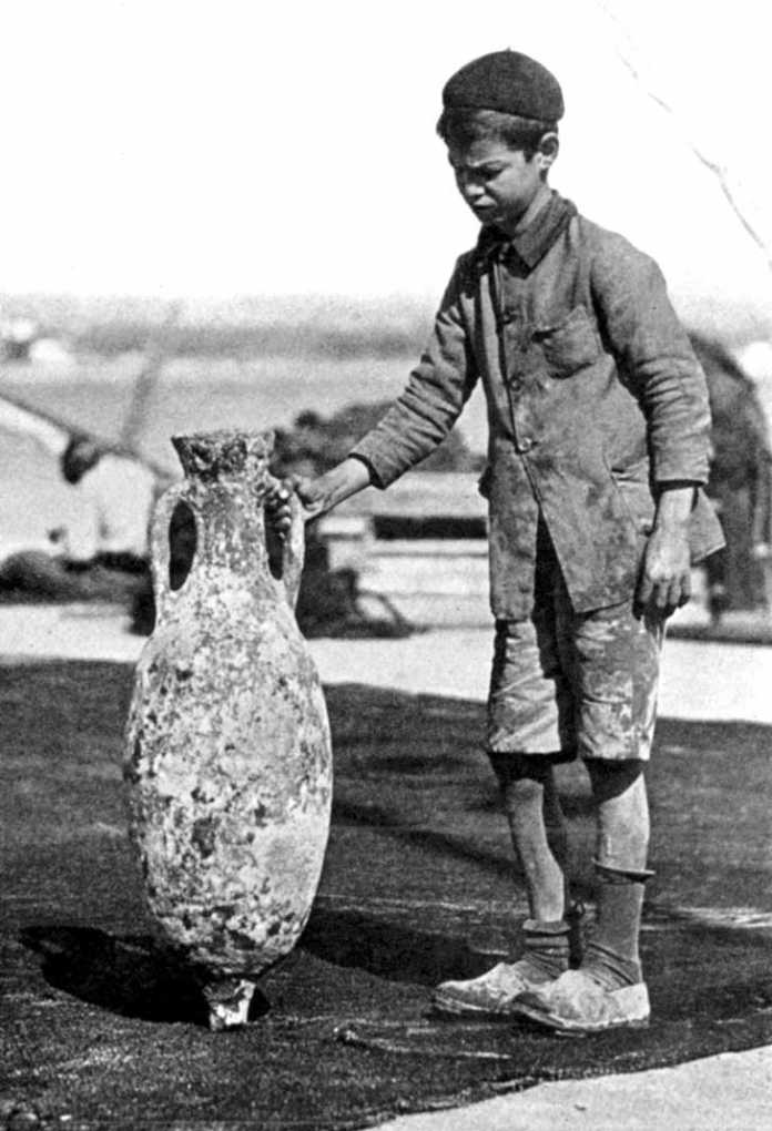Un joven pescador ibicenco sostiene un ánfora, en una foto de 1928