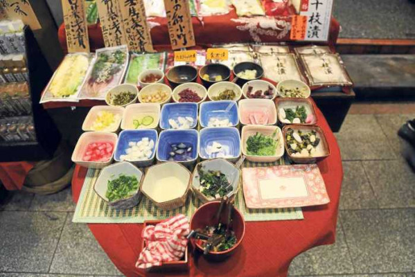 Pequeños platos de degustación de la comida que se puede adquirir, comida fresca envasada y un puesto de ‘sushi’ y ‘sake’ callejero.