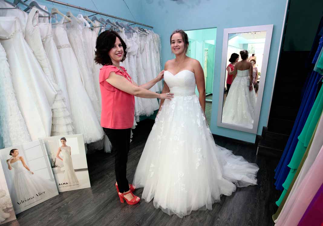 Mariluz Serra junto a una novia probándose uno de los vestidos de la tienda. FOTOS RUBÉN E, IBAÑEZ