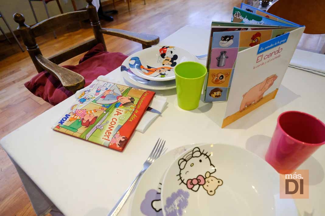 Restaurants Amics de la Infància, con vajilla infantil, cuentos y una trona dispuesta en la mesa