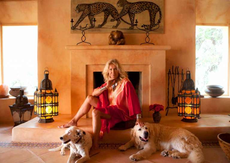 La exmodelo italiana Isa Stoppi posa ante la chimenea de su casa ibicenca flanqueda por sus perros.