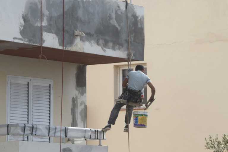 Un operario pinta la fachada de un edificio en Ibiza.